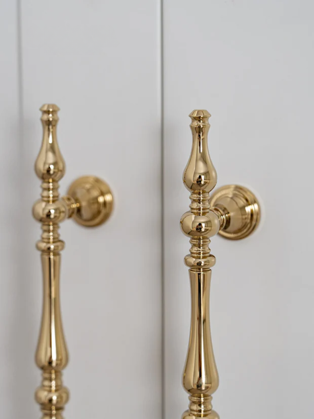 Gold door handles on a light gray door.