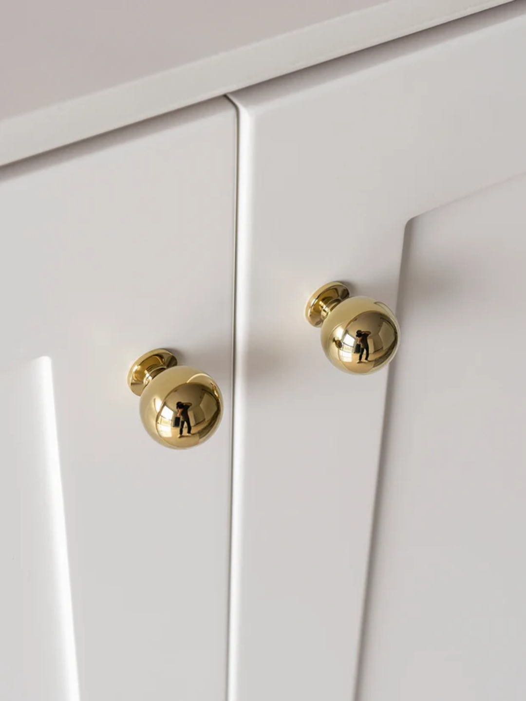 Close-up of white cabinet doors with gold knobs
