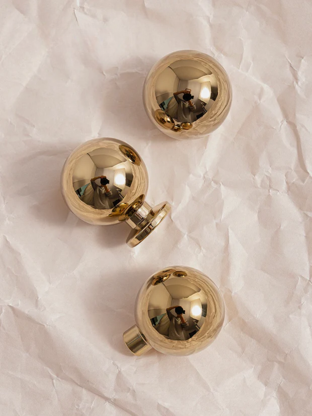 Three gold spherical objects on a textured white surface