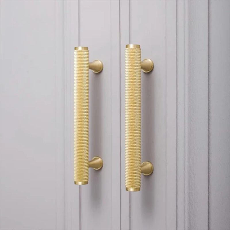 Gold textured cabinet handles on a gray wooden door