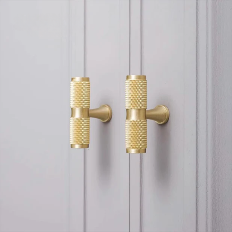 Gold cabinet handles on a gray wooden door