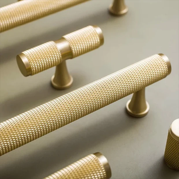 Gold cabinet handles with textured design on a neutral background