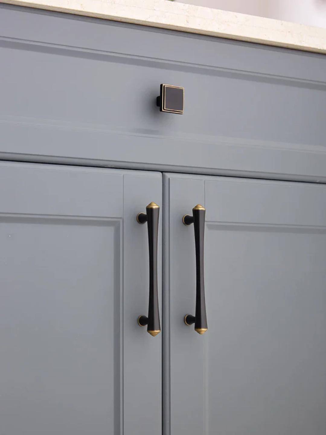 Gray cabinet with black handles and gold accents