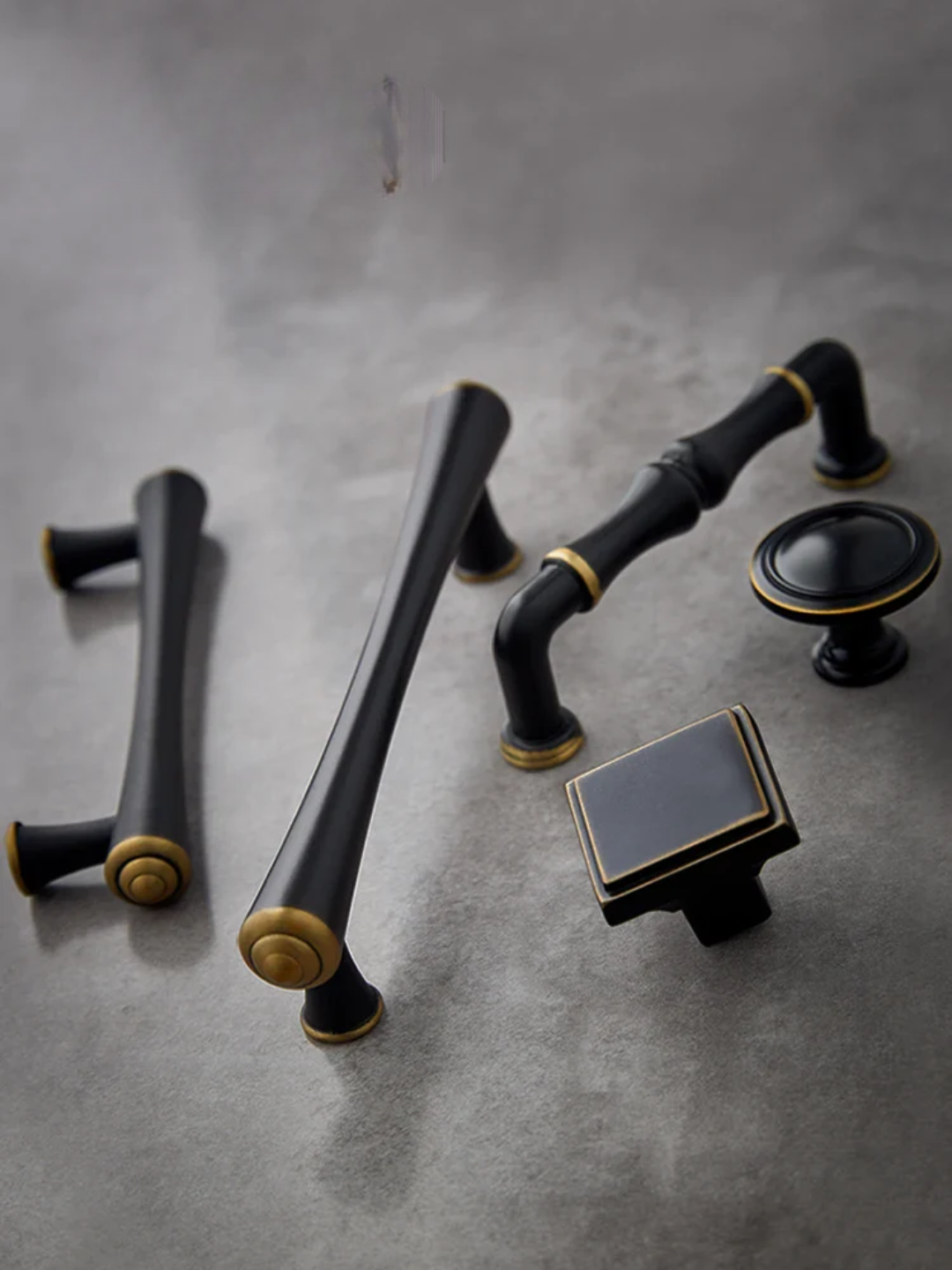 Set of black and gold cabinet handles on a gray surface