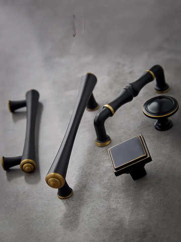 Set of black and gold cabinet handles on a gray surface
