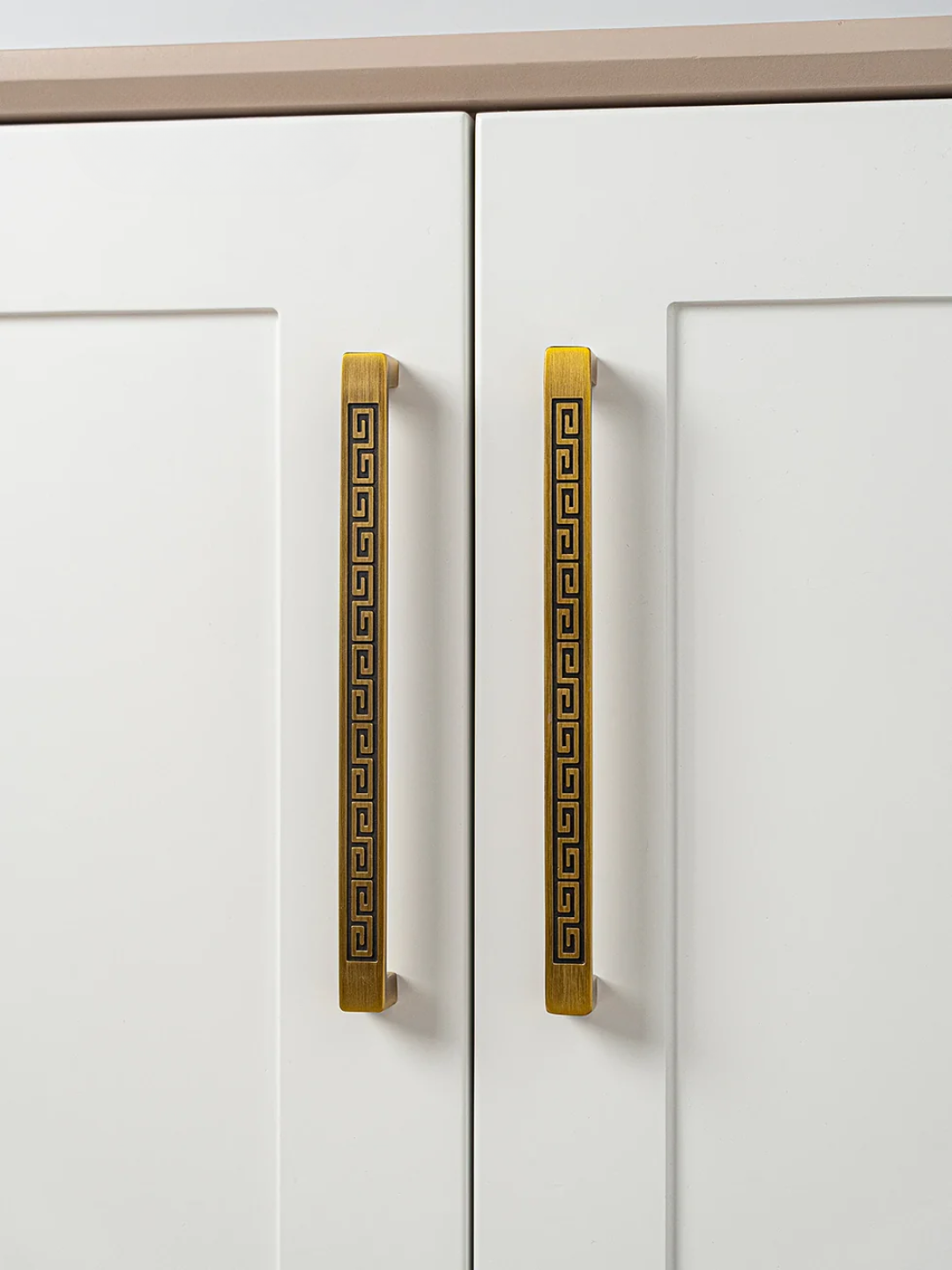 White cabinet doors with gold decorative handles on a neutral background