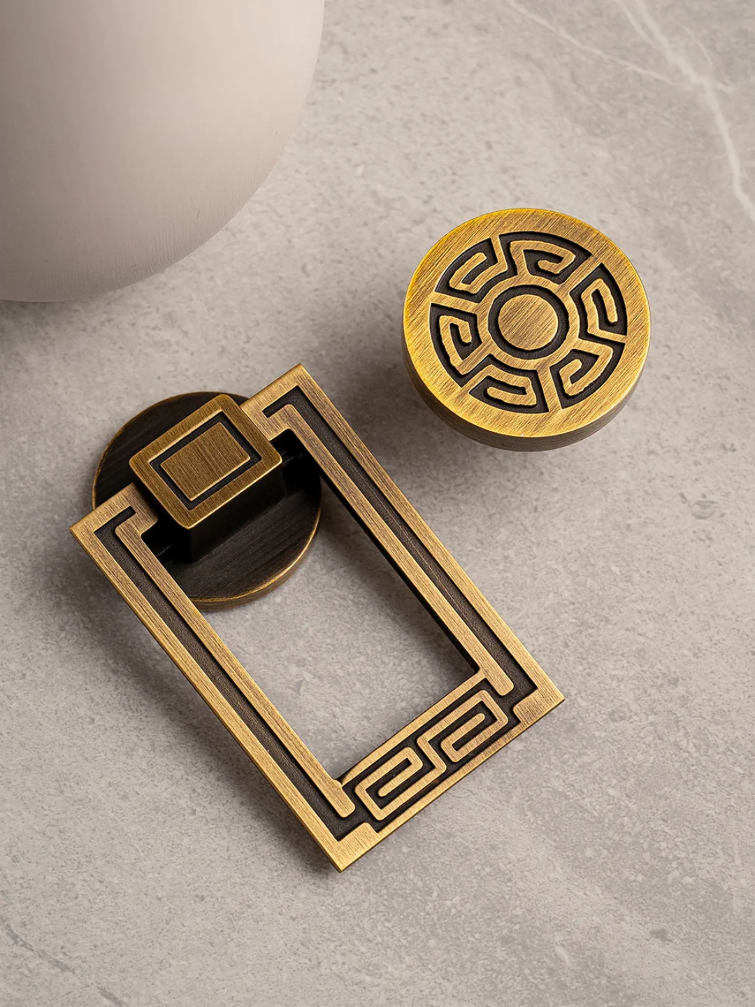 Brass door handle and decorative disc on a gray surface.