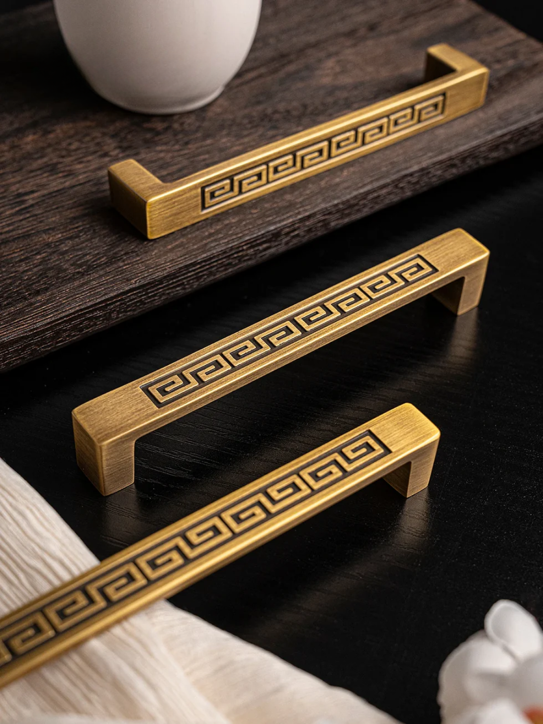 Gold cabinet handles with decorative patterns on a dark surface, featuring the Santaya brand.
