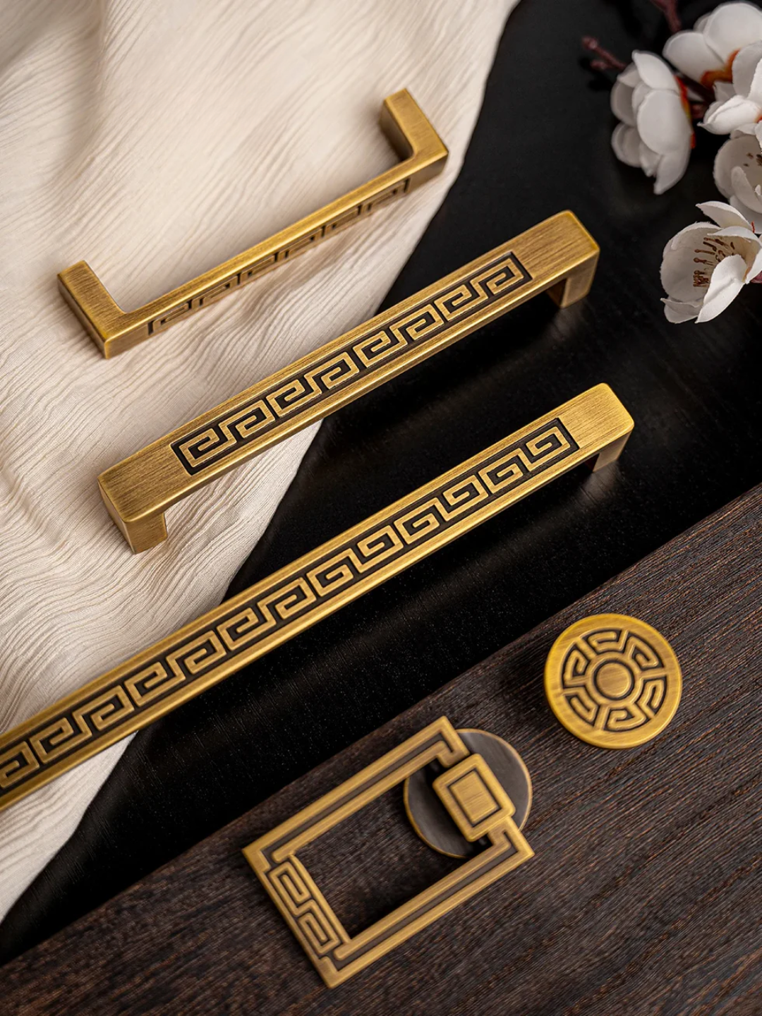 Set of gold cabinet handles with decorative patterns on a wooden surface.