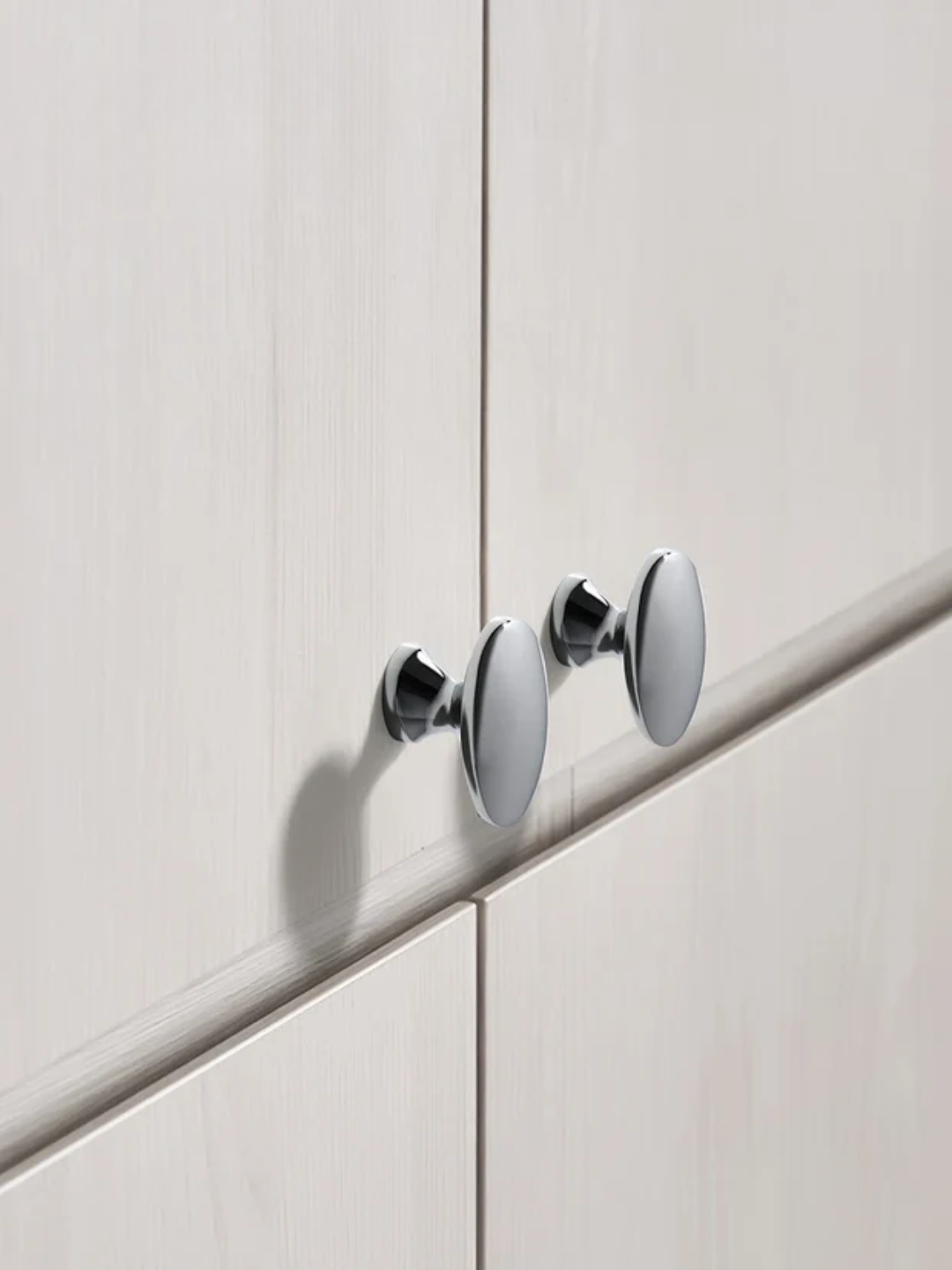 Close-up of a modern cabinet handle on a light wood panel.