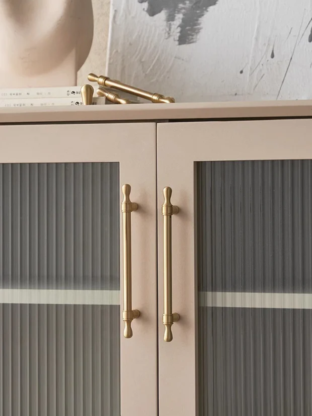 Cabinet with glass doors and gold handles on a neutral background