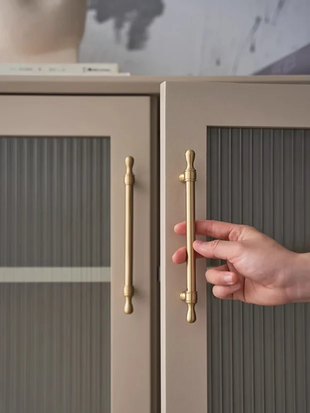 Hand opening a cabinet door with gold handles, featuring Santaya luxury hardware.