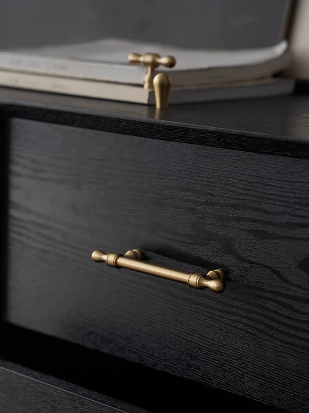 Black wooden drawer with brass handles on a dark background