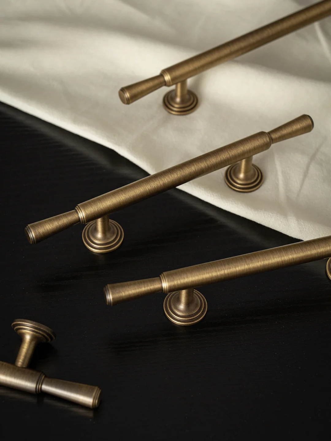 Set of brass cabinet handles on a wooden surface with a map and decorative frame in the background.