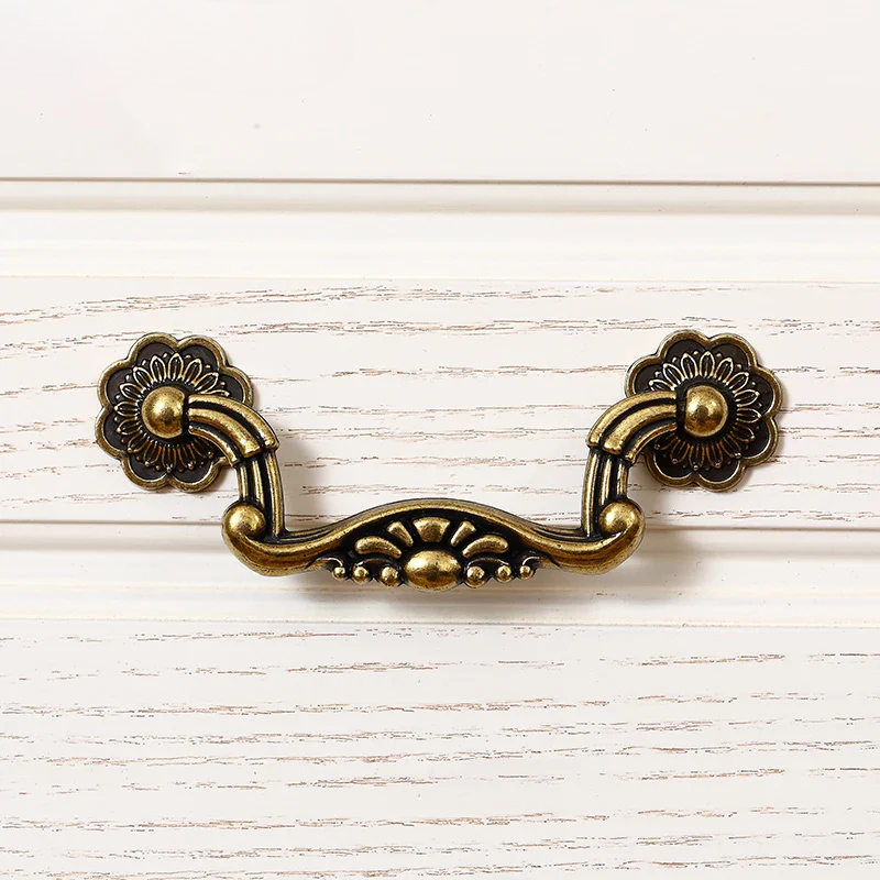 Decorative brass cabinet handle on a white wooden background