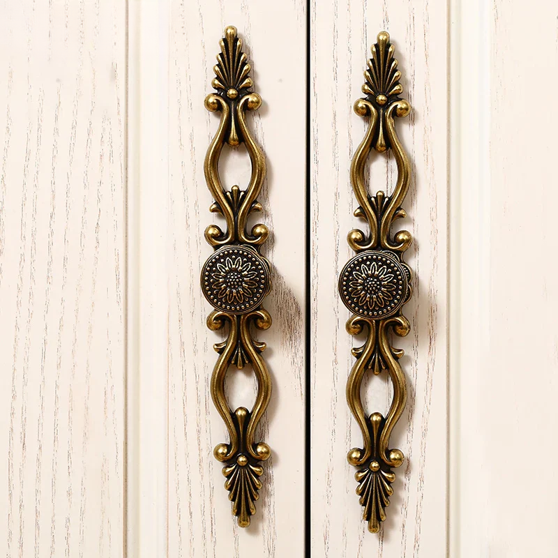 Decorative brass cabinet handles on a white wooden background
