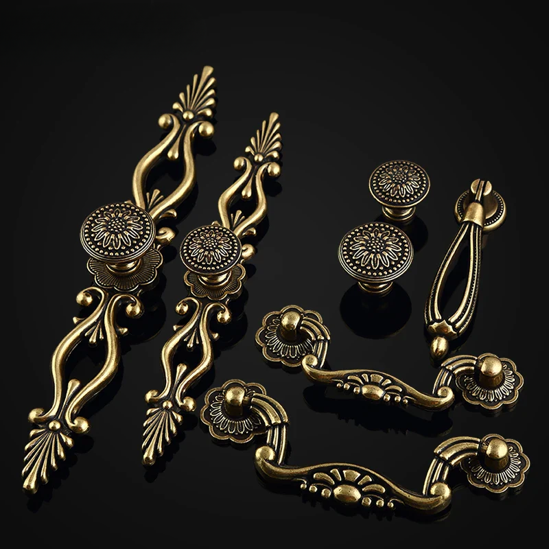 Set of ornate brass cabinet handles and knobs on a black background