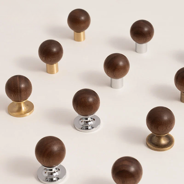 Set of wooden knobs with gold, silver, and bronze bases on a white background
