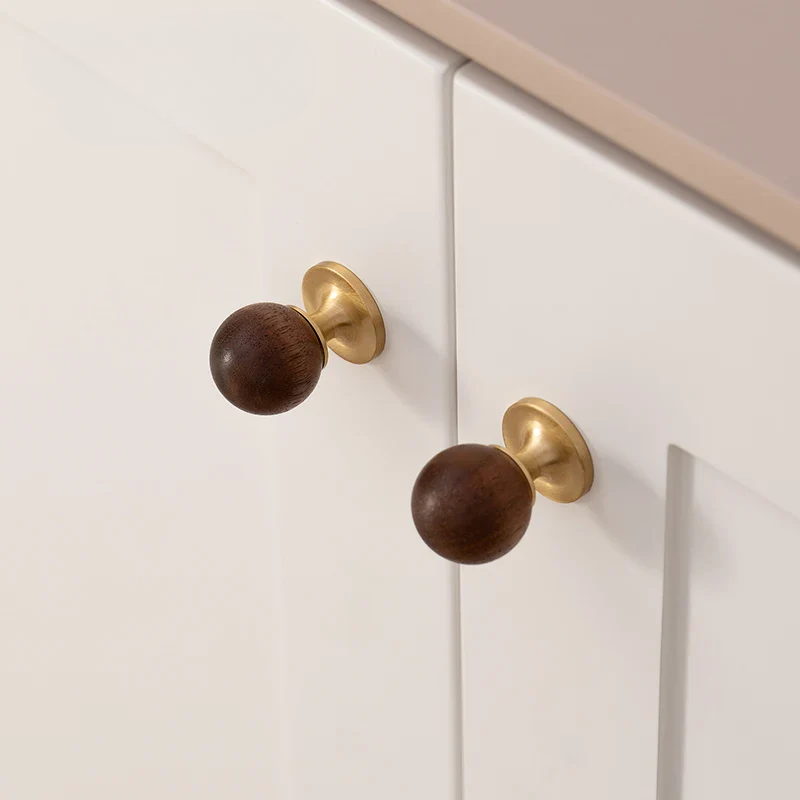 Close-up of wooden knobs on a white cabinet door with gold hardware.