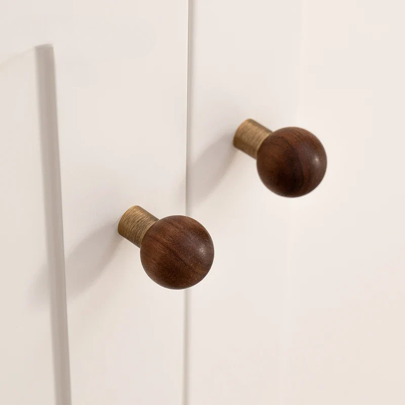 Two wooden knobs on a white cabinet door.
