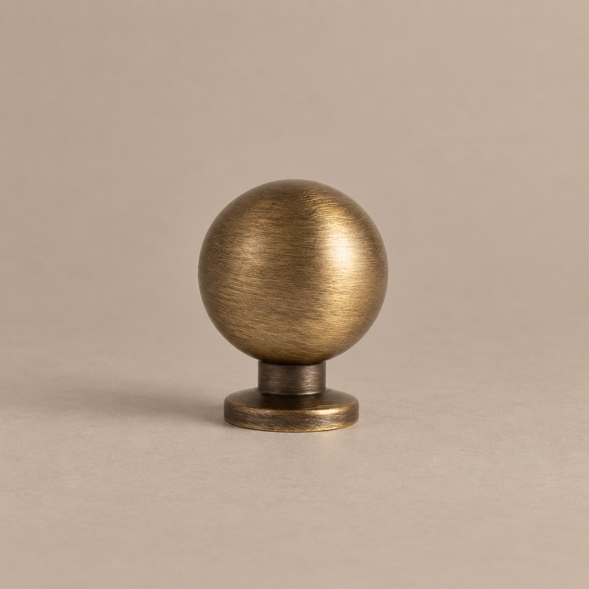 antique brass ball knob on a warm taupe studio surface