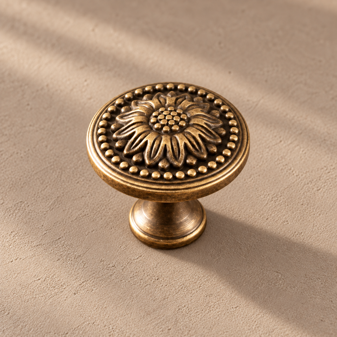 Solid Brass Chrysanthemum Cabinet Knob — Antique Brass on a neutral stone studio background