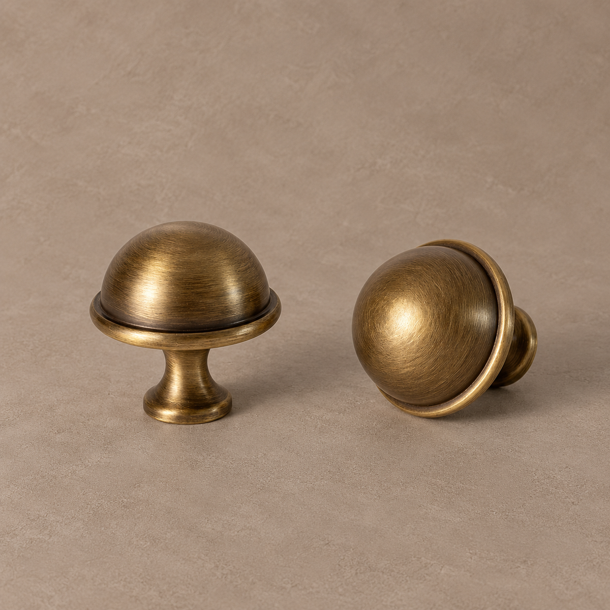 antique brass dome knob with narrow raised rim, flared neck and circular base on a warm taupe studio background