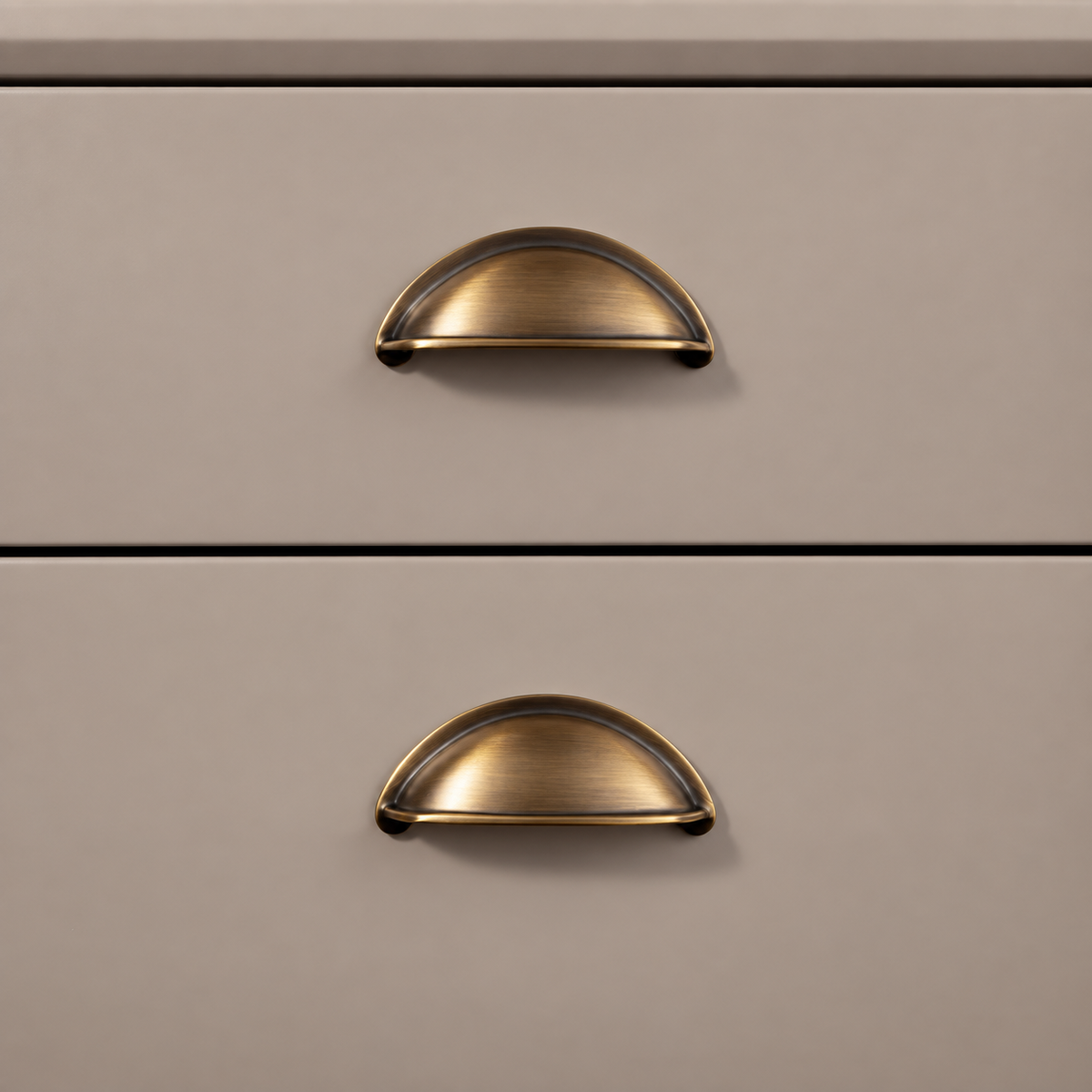 Antique brass cup pulls installed on taupe drawer fronts
