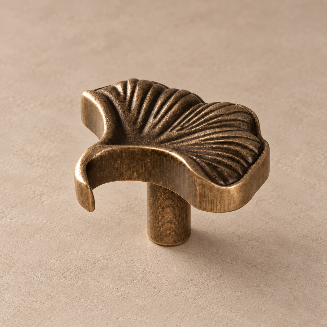 Solid Brass Ginkgo Leaf Cabinet Knob — Antique Brass on a neutral stone studio background