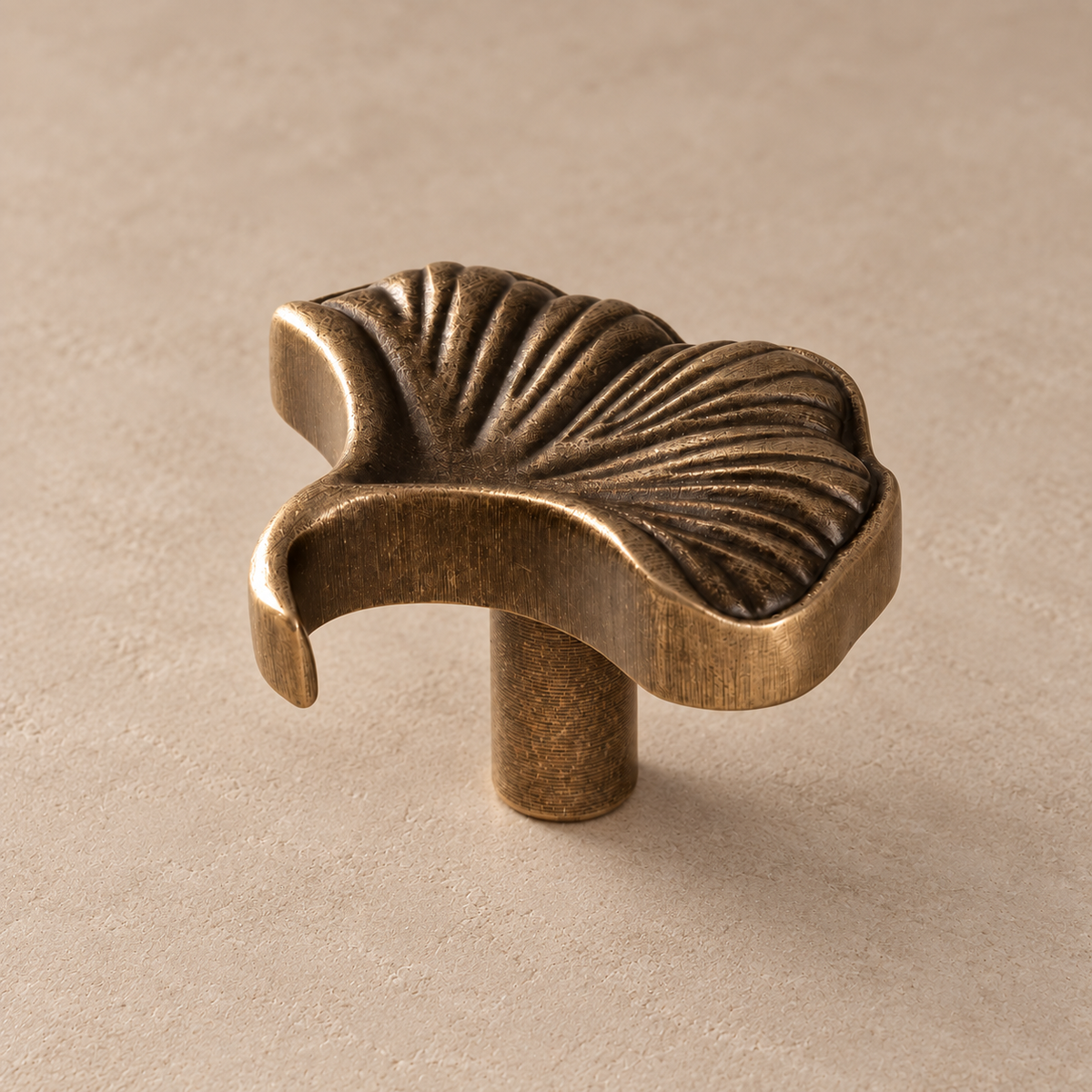 Antique brass ginkgo leaf cabinet knob — side detail on taupe plaster
