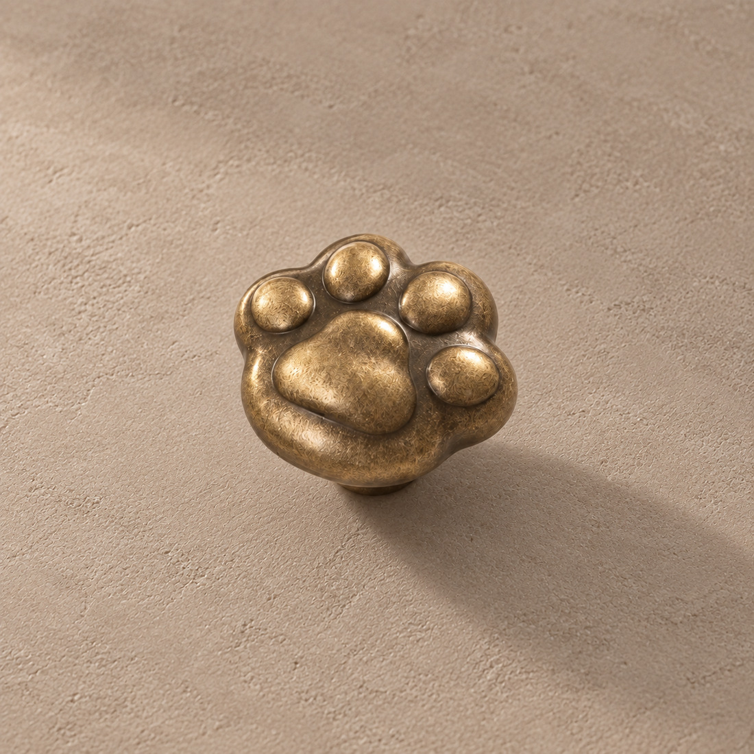 Solid Brass Cat Paw Cabinet Knob — Antique Brass on a neutral stone studio background