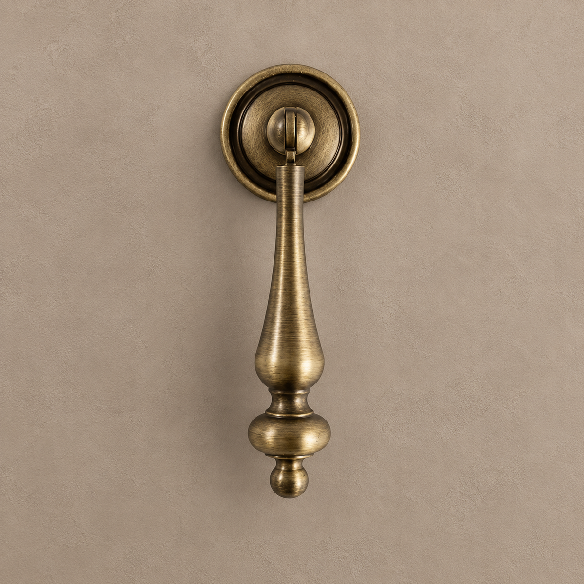 Antique brass large pendant cabinet pull with round backplate on a warm taupe background