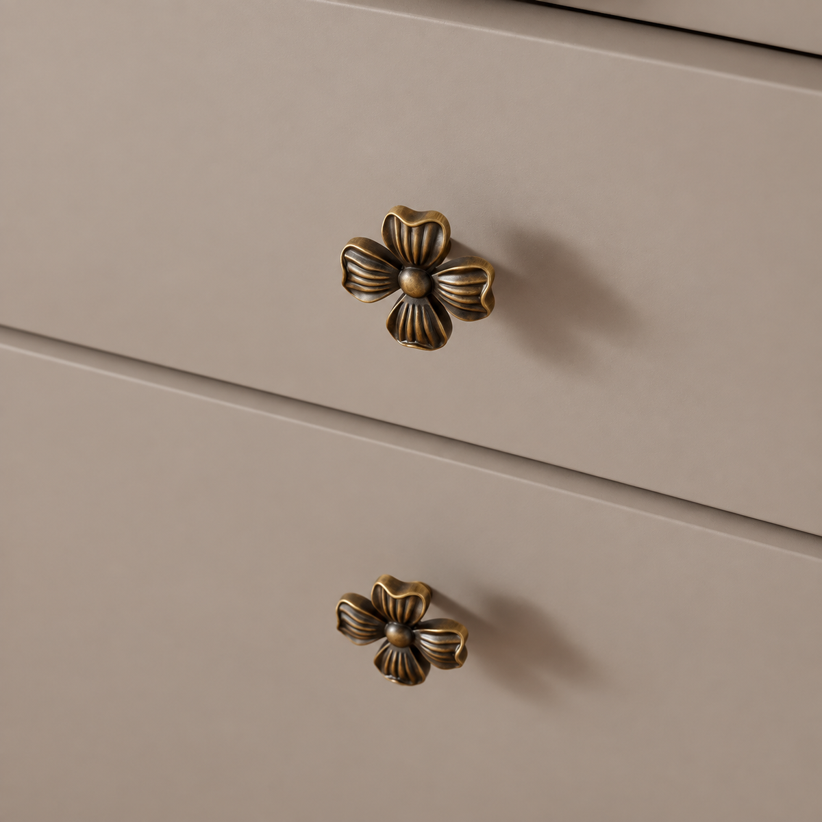 Antique brass four-petal cabinet knob — installed on taupe drawers