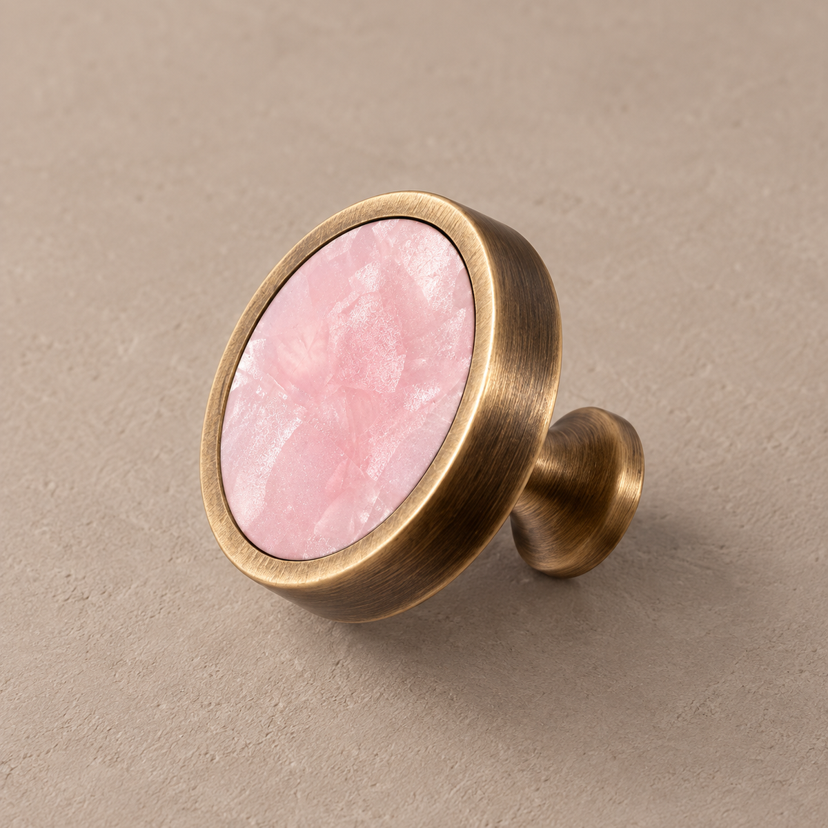 Antique brass cabinet knob with pink inlay on taupe studio background