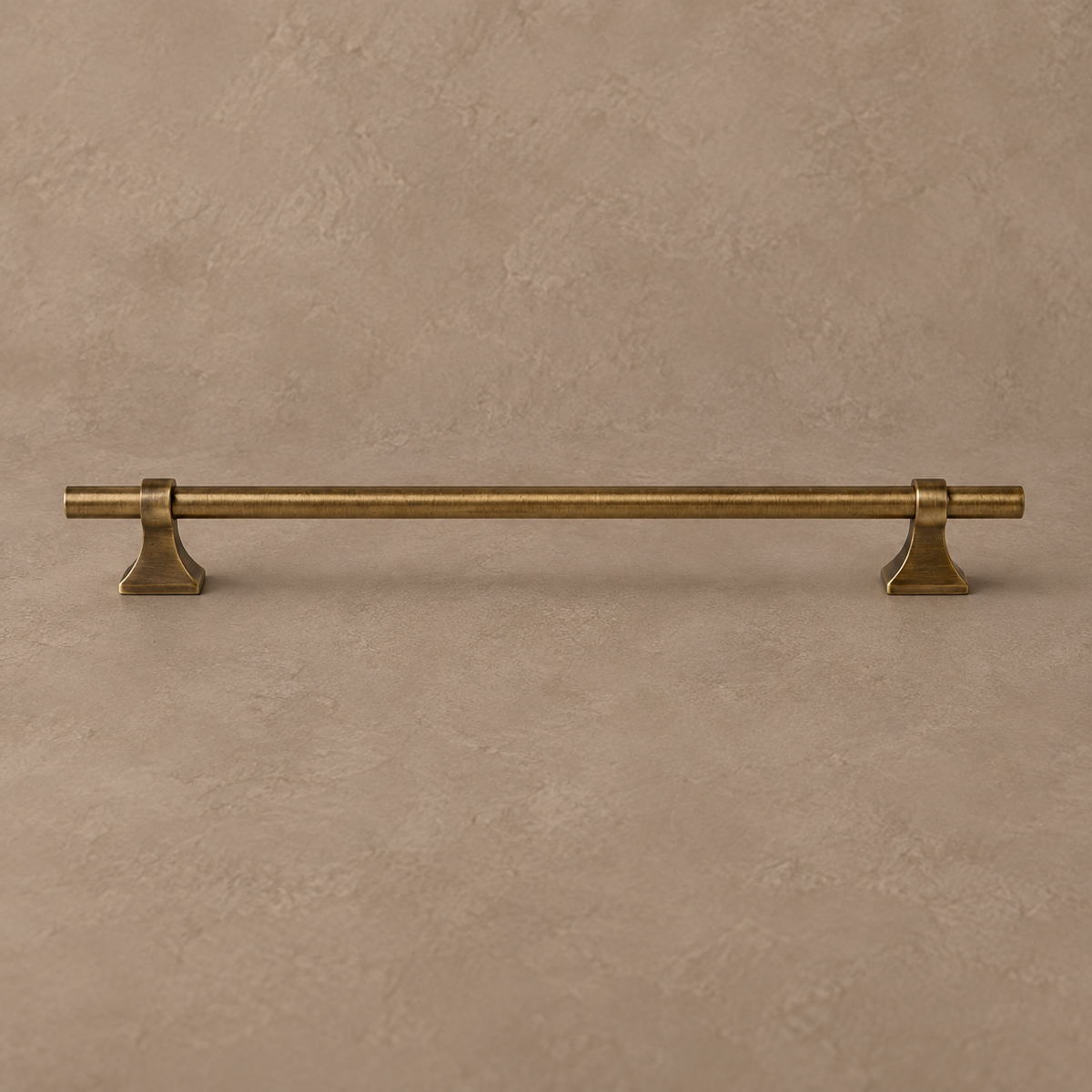 Antique brass cabinet pull on a warm taupe studio background