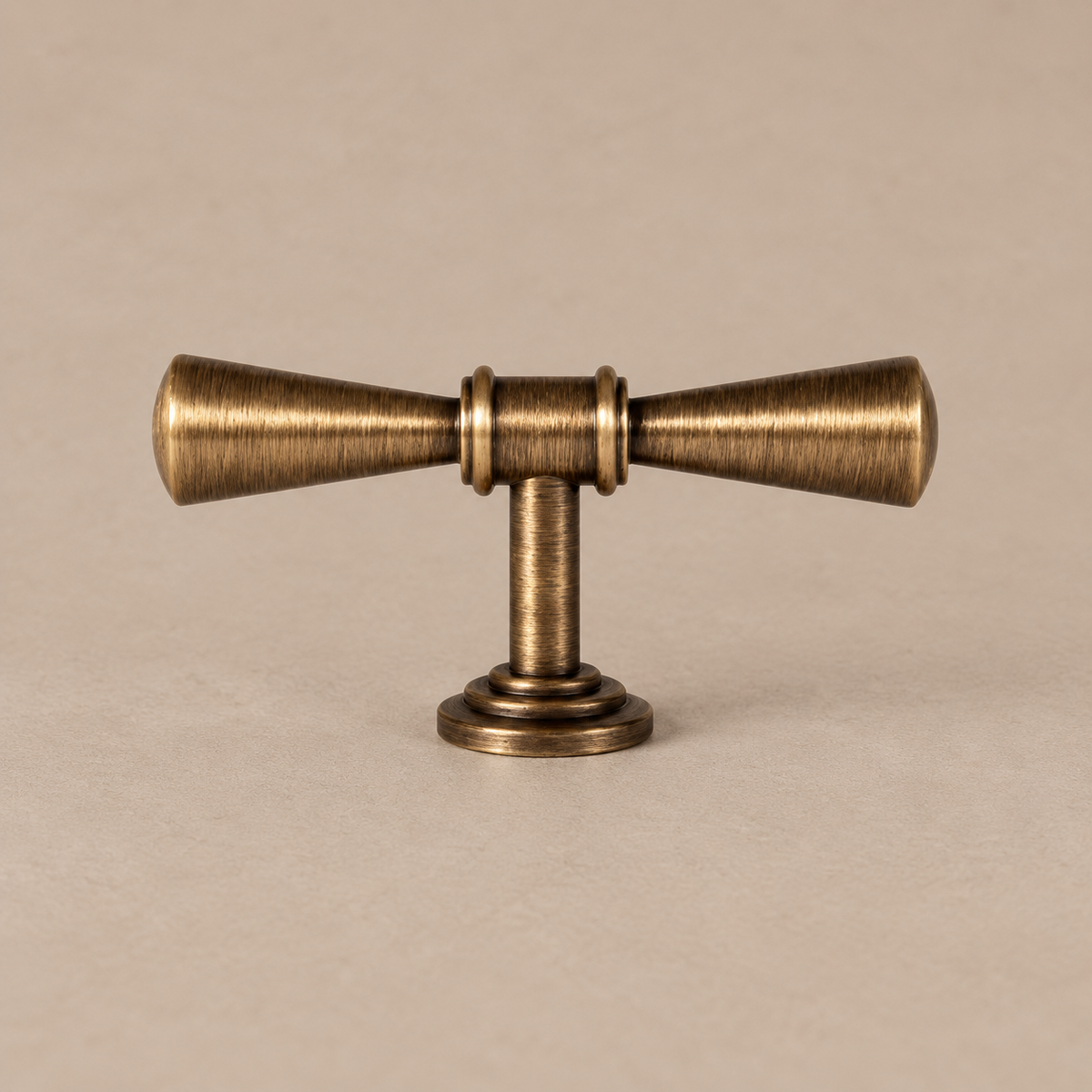 antique brass trumpet t knob on a warm taupe studio surface