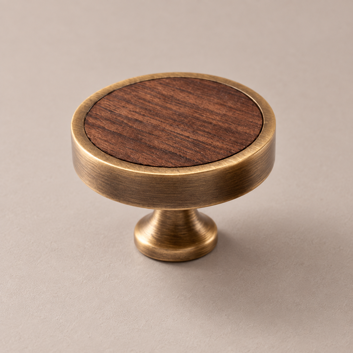 Antique brass cabinet knob with walnut wood inlay on taupe studio background