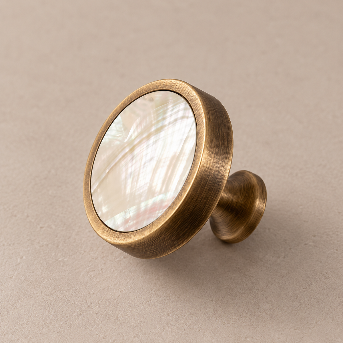 Antique brass cabinet knob with white inlay on taupe studio background