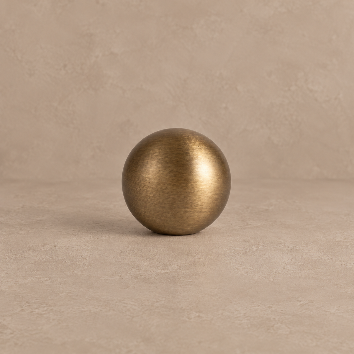 Antique brushed brass round cabinet knob on a warm taupe studio background