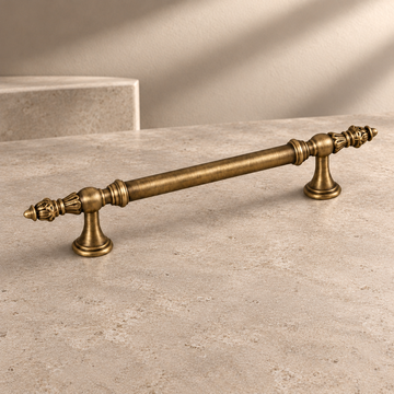 Tapered Spindle Cabinet Pull & Knob — Antique Brass on a neutral stone studio background