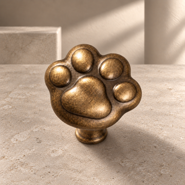 Solid Brass Cat Paw Cabinet Knob — Antique Brass on a neutral stone studio background