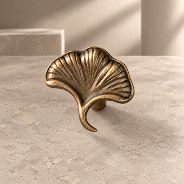 Solid Brass Ginkgo Leaf Cabinet Knob — Antique Brass on a neutral stone studio background