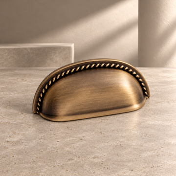 Antique Brass Shell-Shaped Thumb Cabinet Pull — Modern Design on a neutral stone studio background