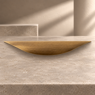 Solid Brass Leaf Cabinet Pull — Antique Brass on a neutral stone studio background