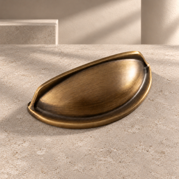 Antique Brass Solid Brass Cabinet Cup Pull — Modern Design on a neutral stone studio background