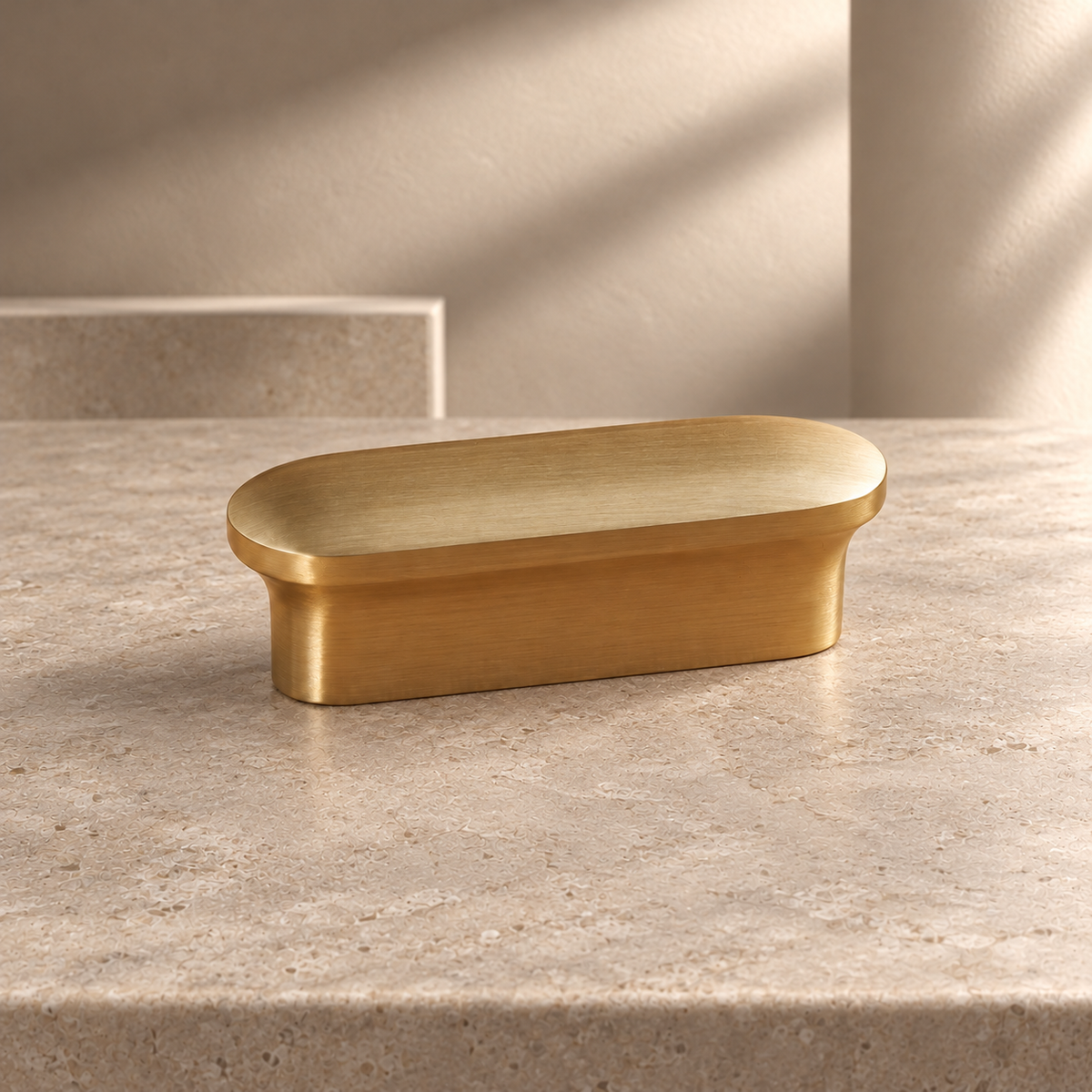 Brass oblong cabinet knob and pull on a neutral stone studio background