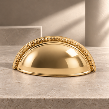 Polished Brass Shell-Shaped Cabinet Pull — Modern Design on a neutral stone studio background