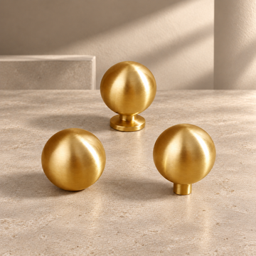 Solid Polished Brass Round Cabinet Knob — Minimalist Ball Design on a neutral stone studio background