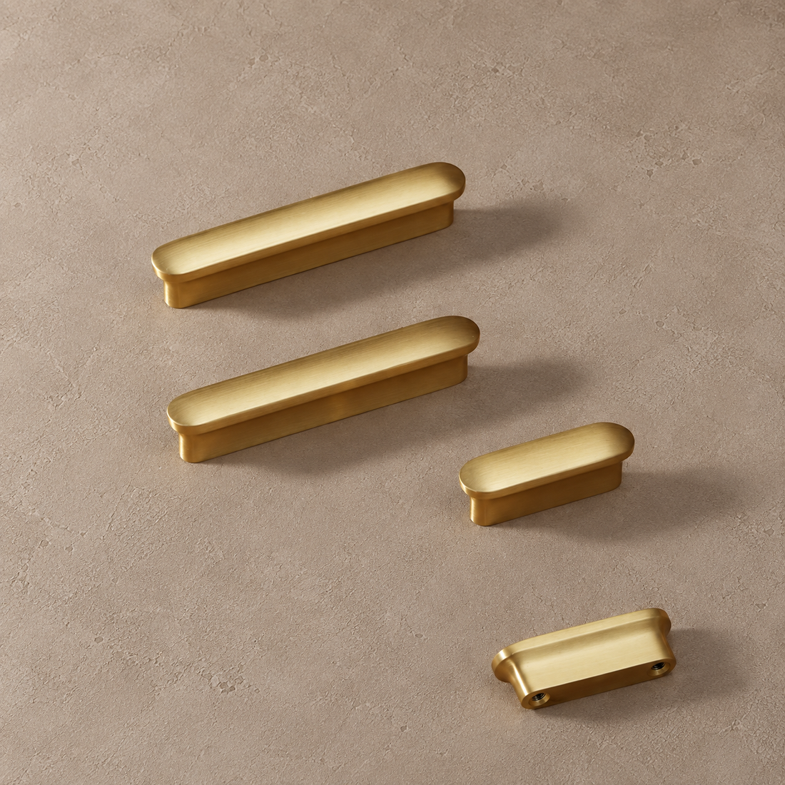 Brass oblong cabinet knob and pull on a neutral stone studio background