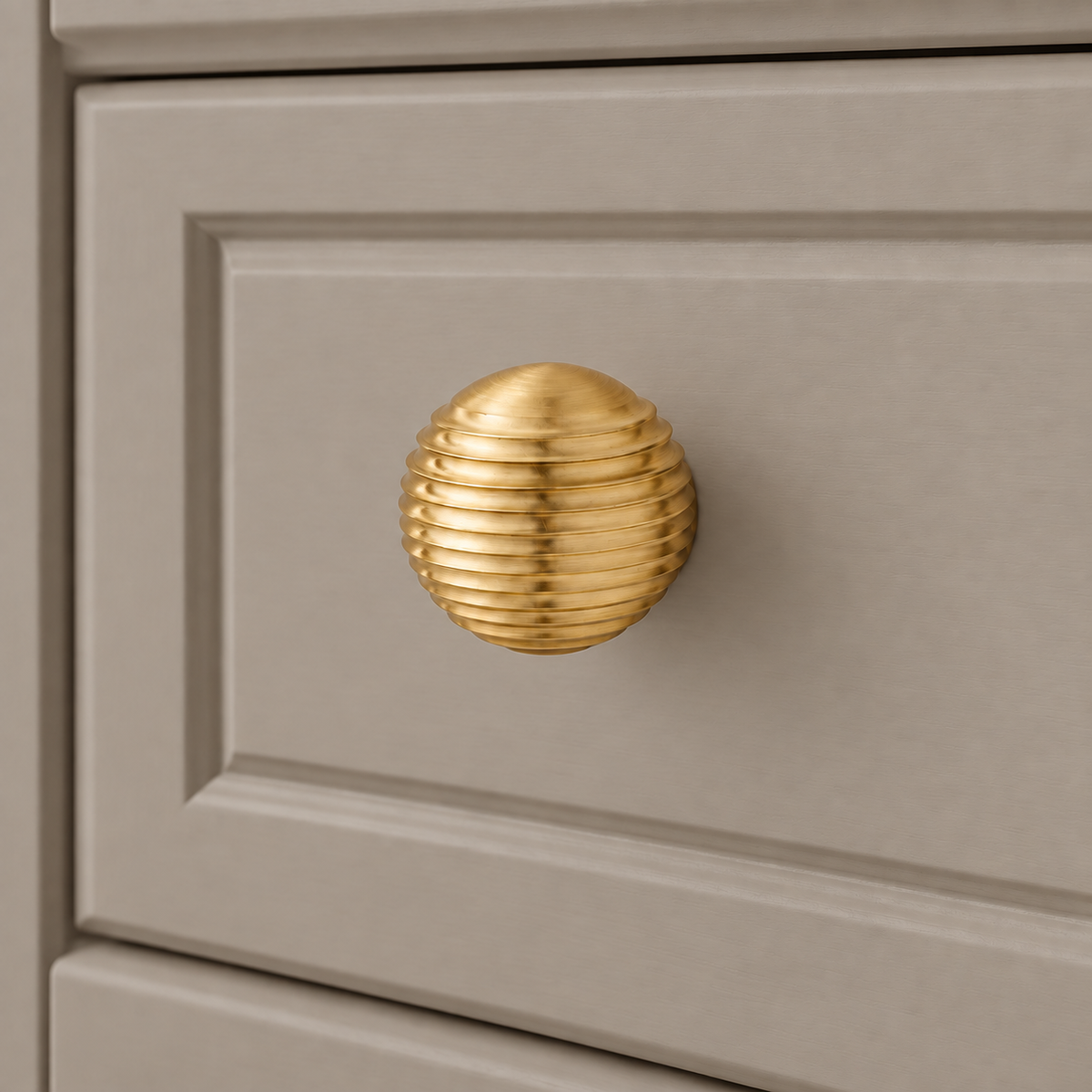 Gold brass thread-ball cabinet knob — installed on taupe cabinet